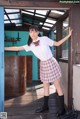 A woman in a school uniform leaning against a door.