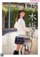 A woman in a school uniform standing next to a bicycle.