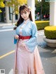 A woman in a blue and pink hanbok is posing for a picture.