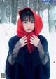 A woman in a red hooded cloak standing in the snow.