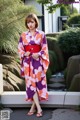 A woman in a purple and orange kimono standing in front of a building.