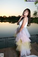 A woman in a white dress standing on a dock by the water.