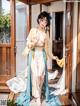 A woman in a blue and white kimono standing on a porch.