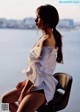 A woman sitting on a chair by the water.