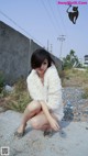 A woman in a white fur coat sitting on the ground.