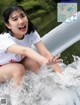 A young woman in a white shirt is sitting in the water.