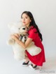 A woman in a red dress holding a white teddy bear.