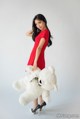 A woman in a red dress holding a white teddy bear.