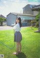 A woman in a school uniform is holding a hose.