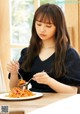 A woman sitting at a table eating spaghetti with a fork.