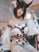 A woman in a cow costume sitting on a bed.