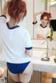 A woman in a white shirt and blue panties standing in front of a mirror.