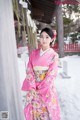 A woman in a pink kimono standing in the snow.